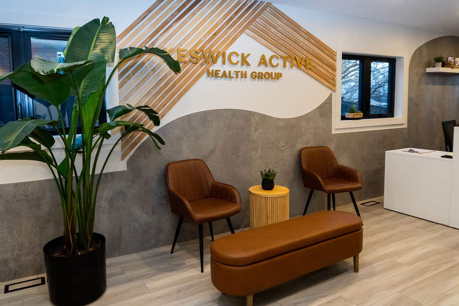 Waiting room at Keswick Active Health Group with brown chairs, sign and coffee table.