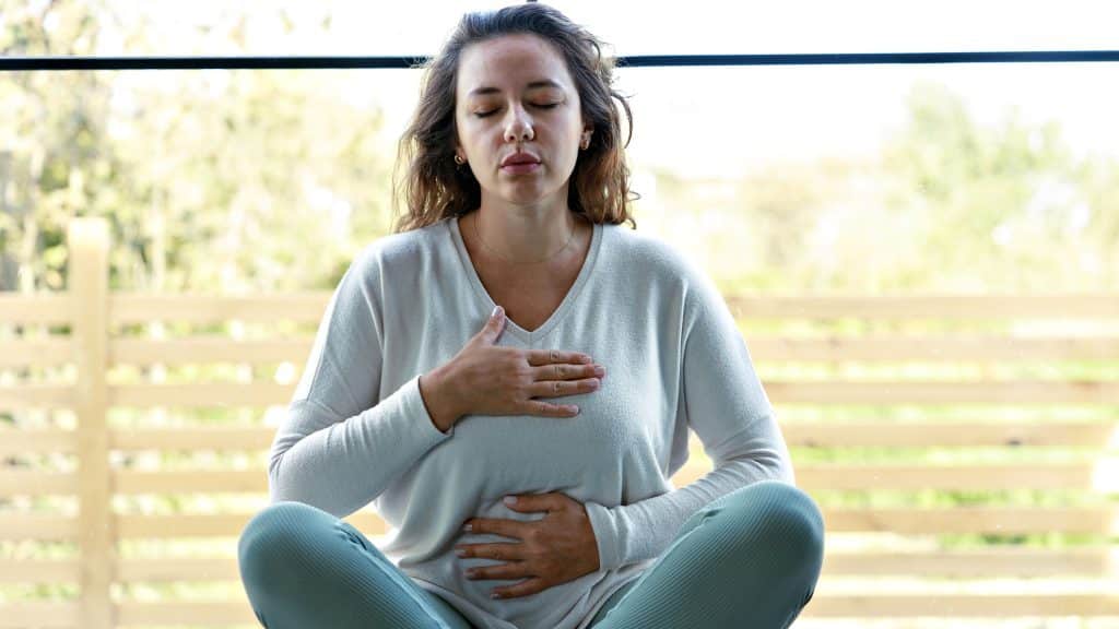 Woman practising deep breathing meditation outdoors